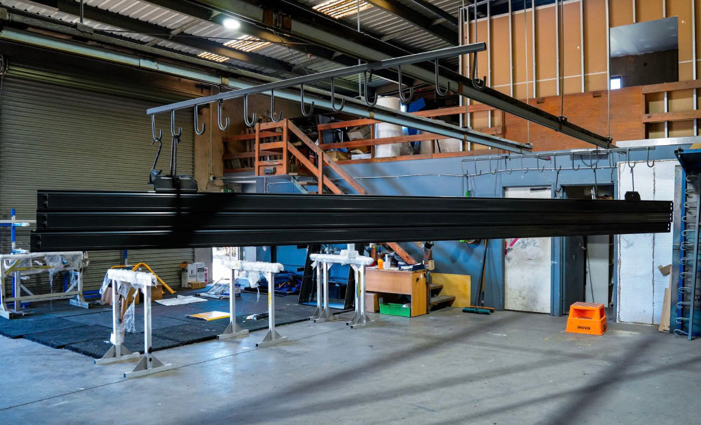 Long metal beam in a warehouse setting with various equipment and materials.